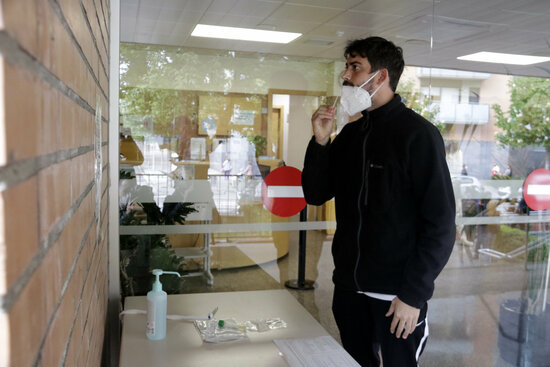 Pla mitjà d'un home fent-se el frotis nasal per a la PCR. Foto: ACN.