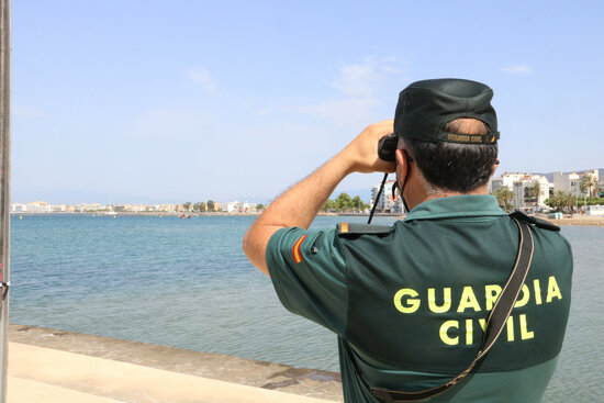 Un agent de la Guardia Civil d'esquenes amb el mar de fons