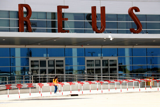 Pla general d'una operària que passa per davant la nova terminal de l'Aeroport de Reus.