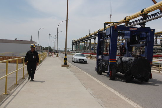 Un treballador passa al costat d'un carretó que transporta una peça al polígon Nord de Repsol a Tarragona. Foto: ACN.