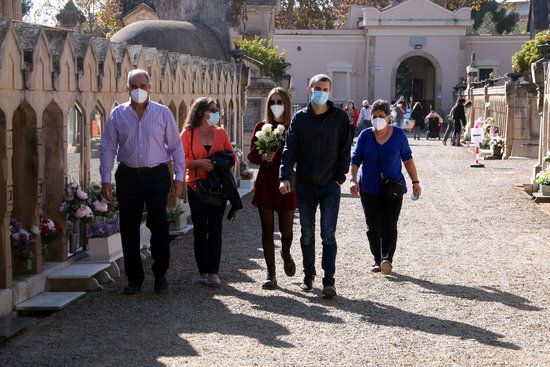 Un grup de persones amb un ram de flors caminant pel cementiri de Tarragona en la festivitat de Tots Sants. Foto: ACN.