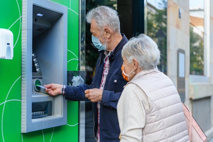 Una parella treu diners d'un caixer automàtic a peu de carrer.